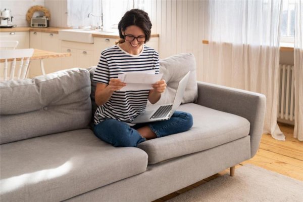 woman sitting on a couch reading a letter